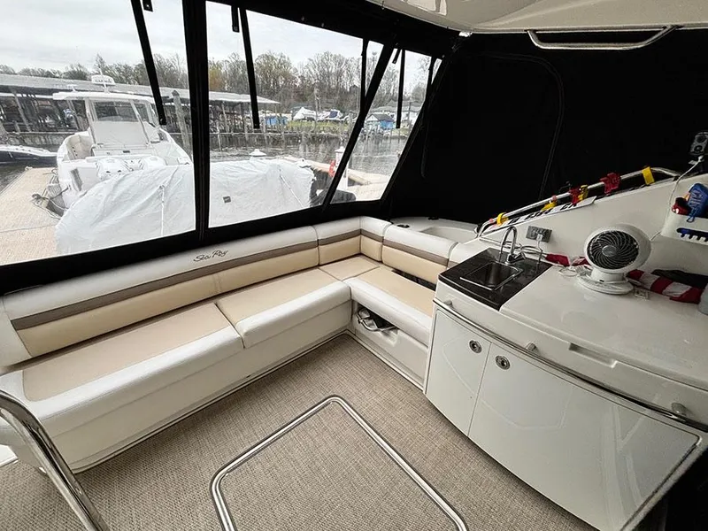 Slide: The Image of 2013 Sea Ray 450 Sedan Bridge interior with seating and kitchenette, docked at marina. - 11
