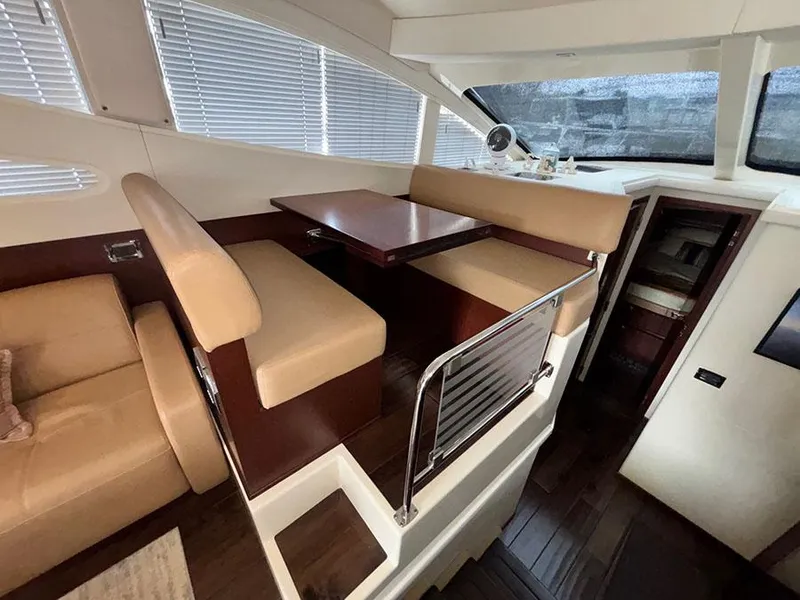 Slide: The Image of Interior of 2013 Sea Ray 450 Sedan Bridge with beige seating and wooden table. - 29