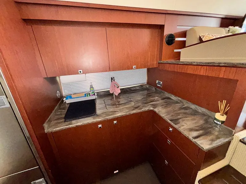 Slide: The Image of 2013 Sea Ray 450 Sedan Bridge kitchen with wood cabinets and marble countertop. - 34