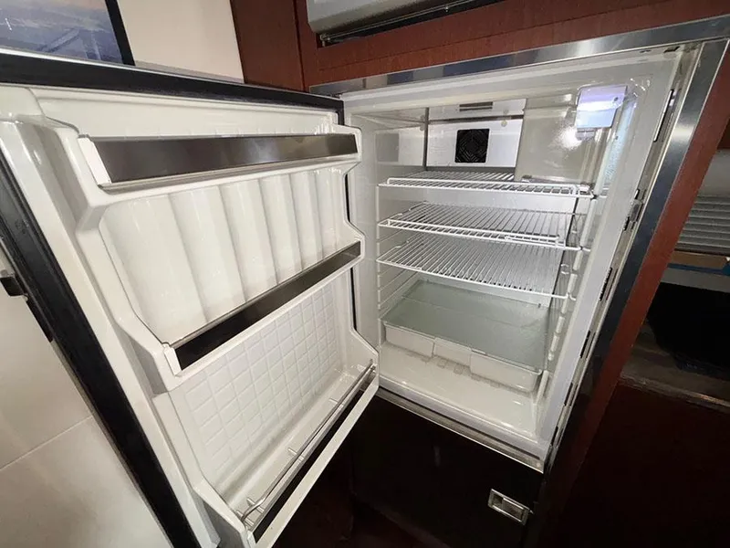 Slide: The Image of Open refrigerator inside 2013 Sea Ray 450 Sedan Bridge yacht, showing empty shelves and door compartments. - 36