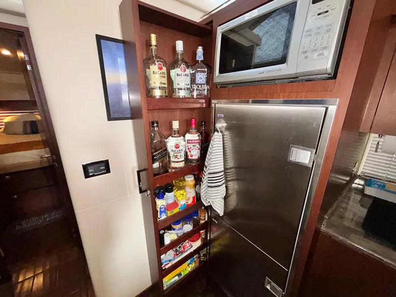 Slide: The Image of Kitchen area in 2013 Sea Ray 450 Sedan Bridge with microwave and stocked pantry. - 38