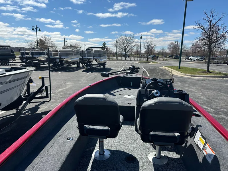 Slide: The Image of 2025 Tracker Super Guide V-16 SC boat in parking lot, clear sky, empty seats. - 2
