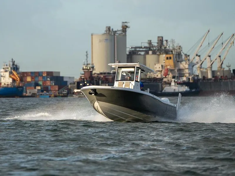 Slide: The Image of 2025 Caymas 291 HB boat cruising in industrial harbor with shipping containers and cranes. - 3