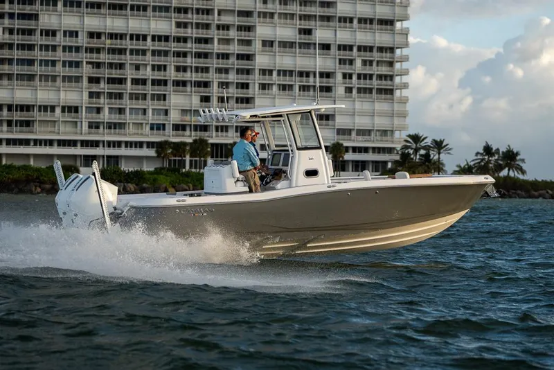 Slide: The Image of 2025 Caymas 291 HB boat cruising on water near a modern building. - 7