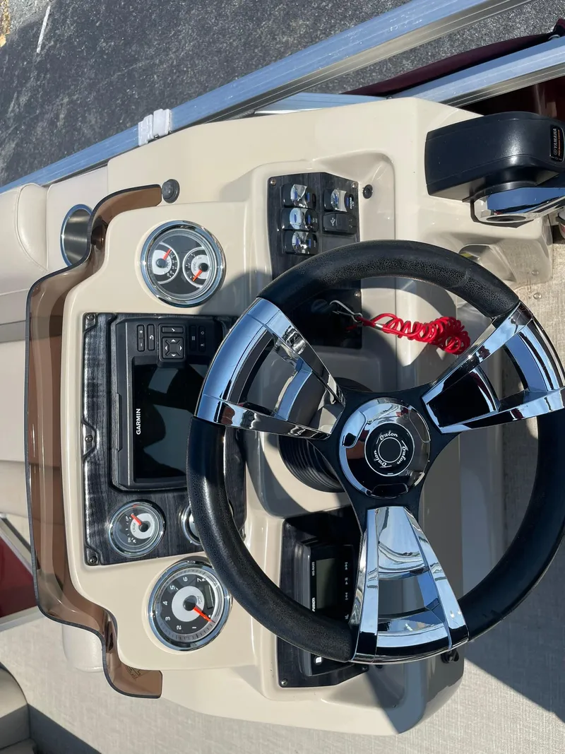 Slide: The Image of Steering console of 2021 Avalon GS Quad Lounger boat with chrome-accented wheel and gauges. - 19