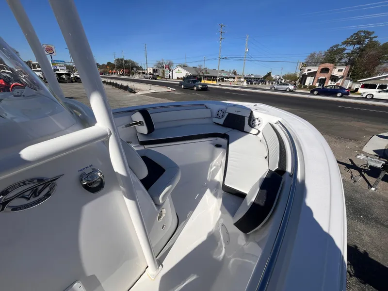 Slide: The Image of 2025 Tidewater 210 CC Adventure boat interior with seating, parked outdoors. - 13