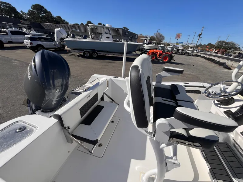 Slide: The Image of 2025 Tidewater 210 CC Adventure boat interior with seating and motor, parked outdoors. - 15