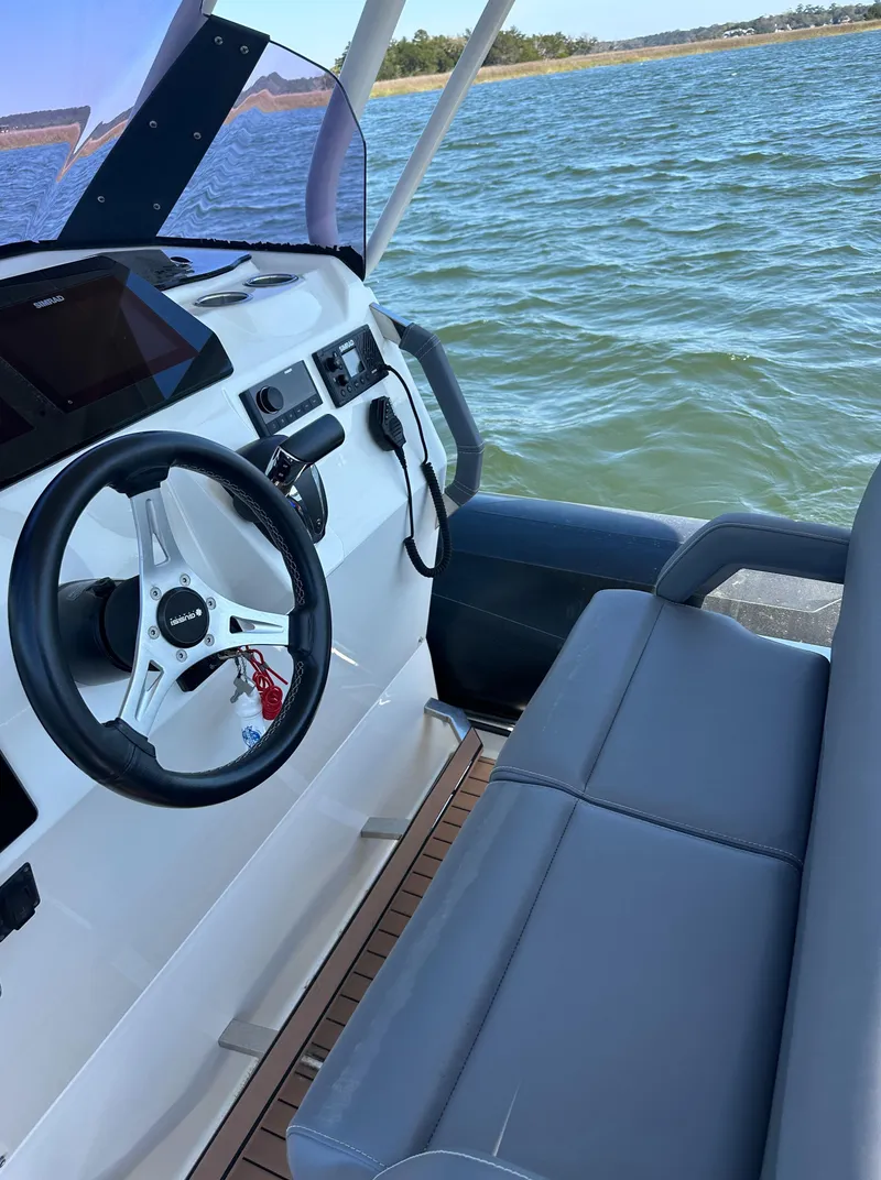 Slide: The Image of 2021 Brig Eagle 8 boat interior with steering wheel and seating, on a calm water backdrop. - 12