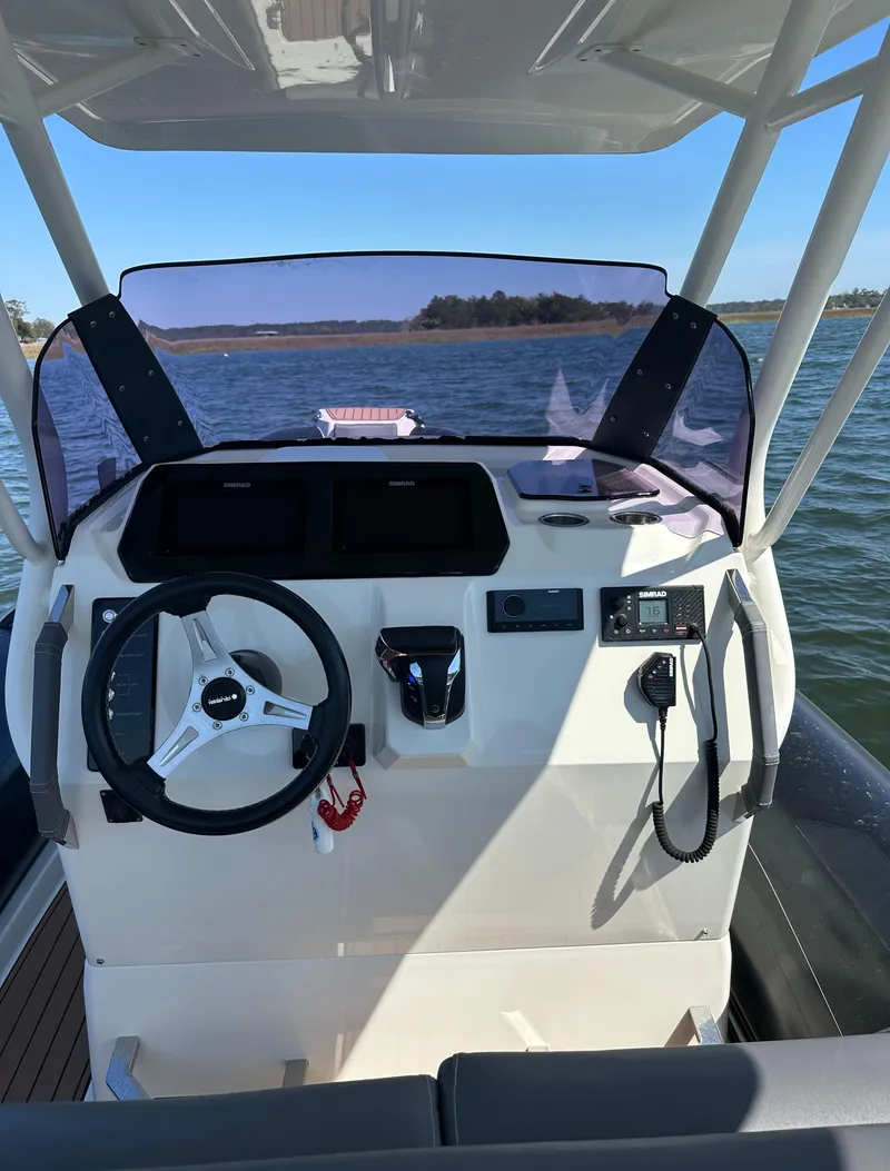 Slide: The Image of 2021 Brig Eagle 8 boat dashboard with steering wheel and controls on open water. - 4