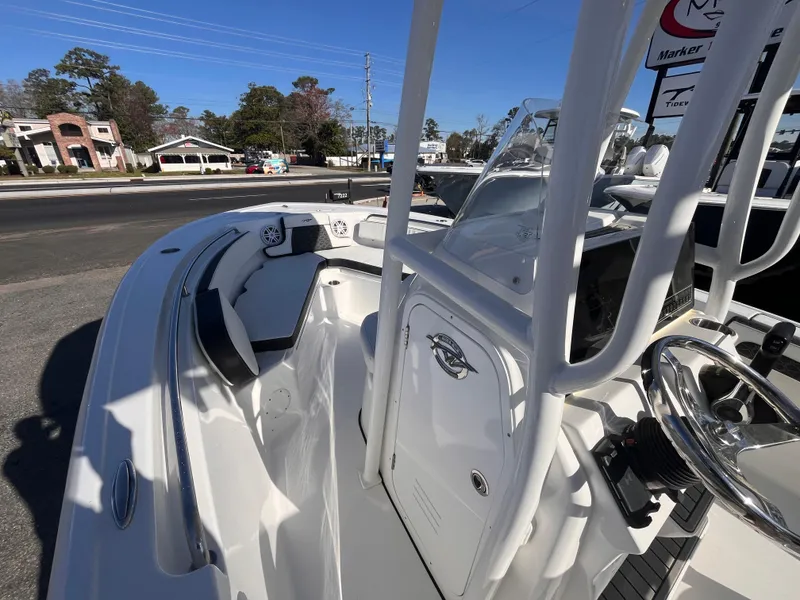 Slide: The Image of 2025 Tidewater 210 LXF boat interior with seating and console, parked outdoors. - 10