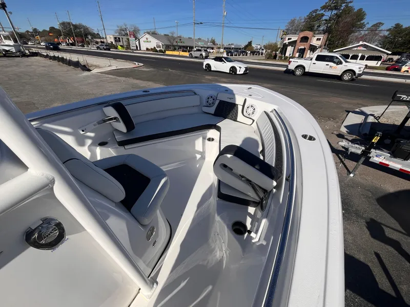 Slide: The Image of 2025 Tidewater 210 LXF boat interior with seating, parked on a trailer in a lot. - 12