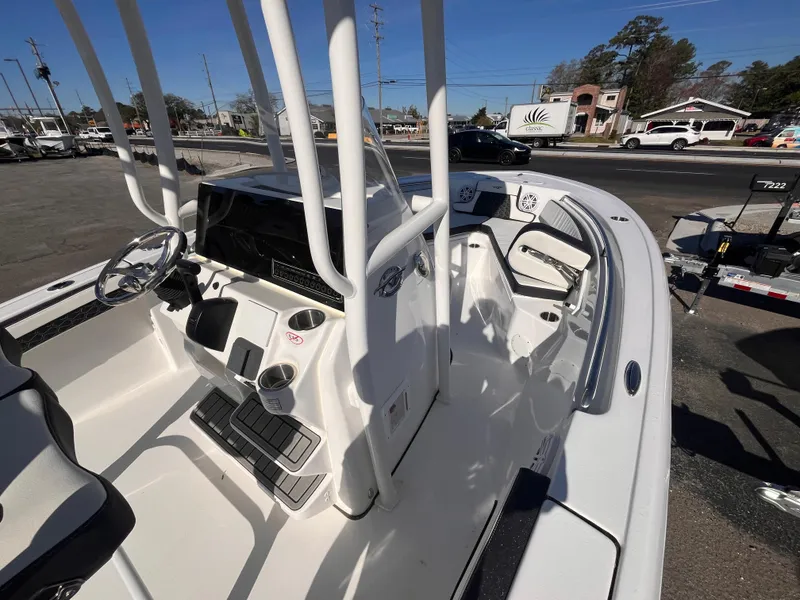 Slide: The Image of 2025 Tidewater 210 LXF boat interior with steering console and seating, parked outdoors. - 13