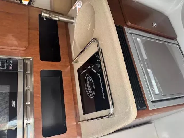 Slide: The Image of 2024 Crownline 270 CR boat interior kitchen with sink, stove, and microwave. - 20