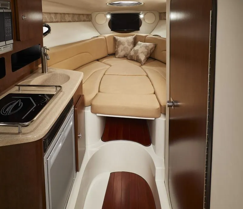 Slide: The Image of 2024 Crownline 280 CRX cabin interior with kitchenette and cozy sleeping area. - 12