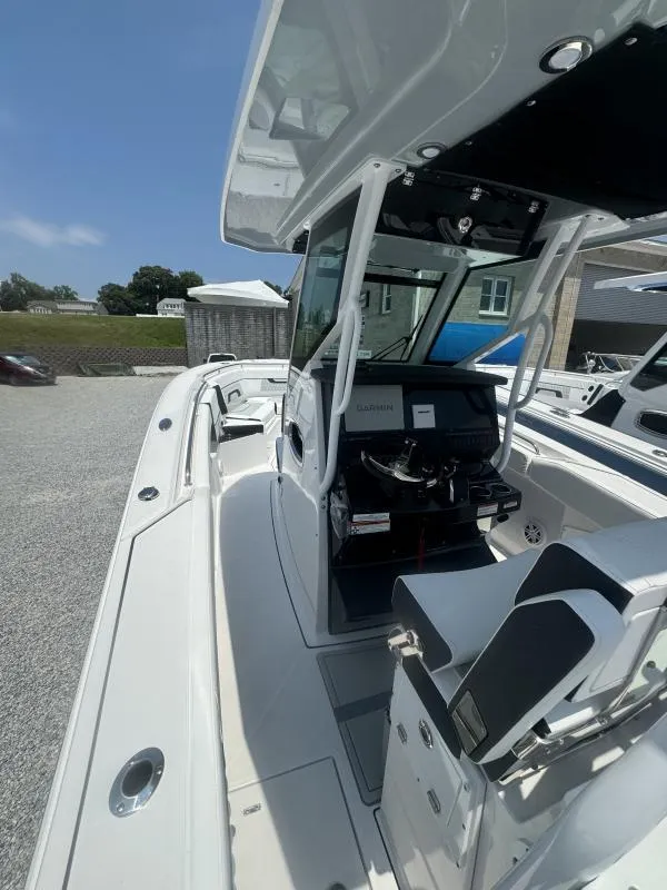 Slide: The Image of 2025 Blackfin 272 CC boat interior with helm and seating, under a clear blue sky. - 13