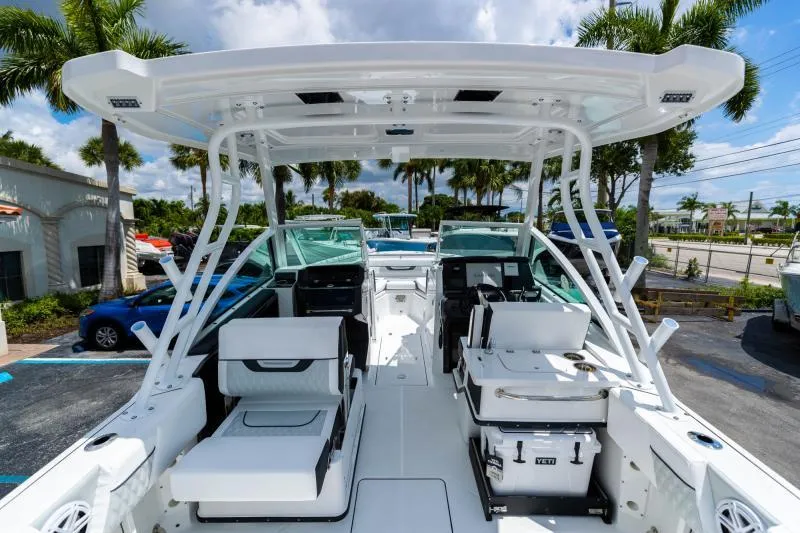 Slide: The Image of 2025 Blackfin 252 DC boat interior with seating, under a clear blue sky and palm trees. - 10