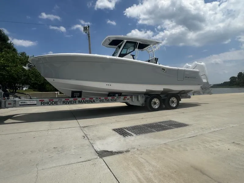 Slide: The Image of 2025 Blackfin 302 CC boat on trailer at Rhode River Marina under a cloudy sky. - 1