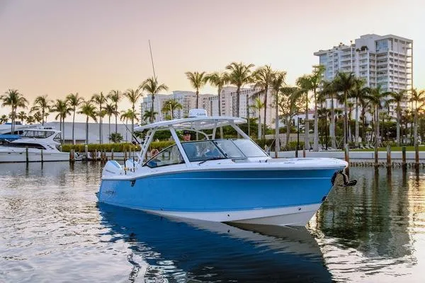 Slide: The Image of 2025 Blackfin 302 DC boat on water, with palm trees and buildings in the background. - 2