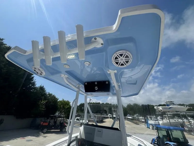 Slide: The Image of 2025 Blackfin 222 CC boat with blue T-top and rod holders, docked under a clear sky. - 10