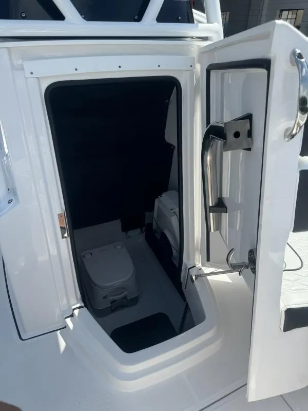Slide: The Image of 2025 Blackfin 222 CC boat interior with open door revealing compact toilet area. - 7