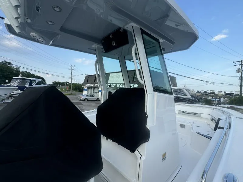 Slide: The Image of 2025 Blackfin 252 CC boat with T-top and console, parked at a dealership. - 7