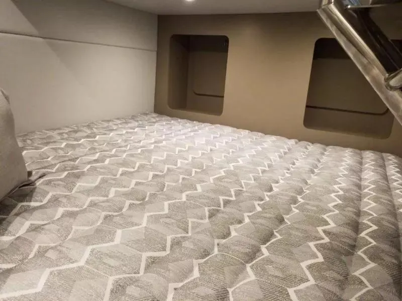 Slide: The Image of 2021 Formula 350 Crossover Bowrider cabin interior with patterned bedding and storage spaces. - 13