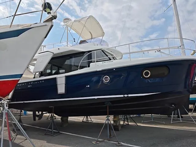 Slide: The Image of 2017 Beneteau Swift Trawler 30 on stands, blue hull, marina setting. - 16