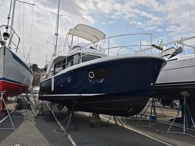 Slide: The Image of 2017 Beneteau Swift Trawler 30 on stands, blue hull, marina setting. - 2