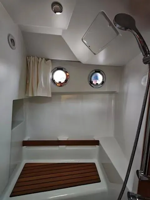 Slide: The Image of 2017 Beneteau Swift Trawler 30 bathroom with shower, portholes, and wooden bench. - 21