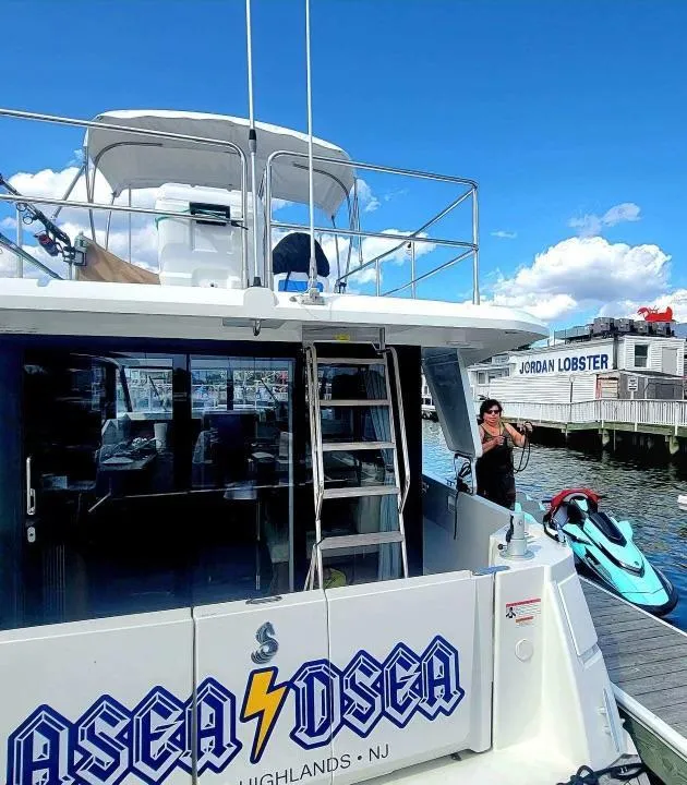 Slide: The Image of 2017 Beneteau Swift Trawler 30 docked, with person and jet ski nearby, clear sky background. - 6
