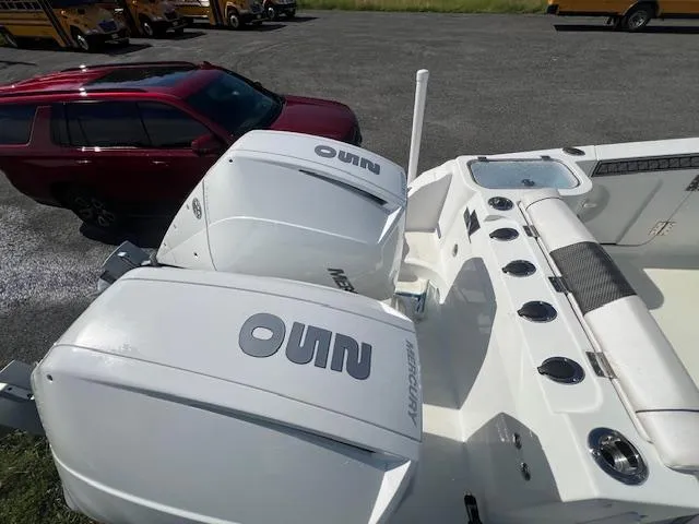 Slide: The Image of 2022 Wellcraft 262 Fisherman boat with dual outboard engines, parked near a red SUV. - 11