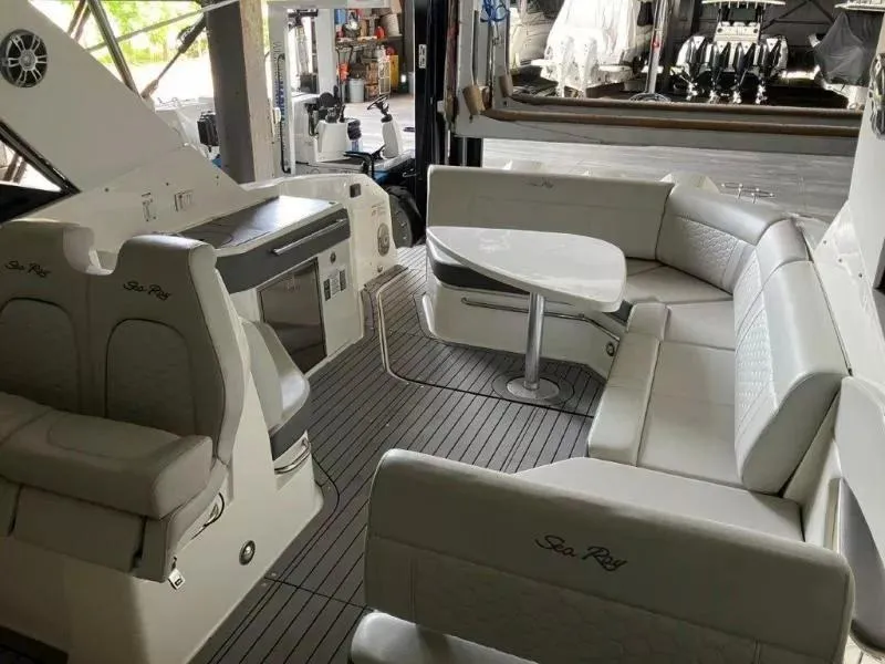 Slide: The Image of 2020 Sea Ray Sundancer 320 OB interior with seating and table in a marina setting. - 18