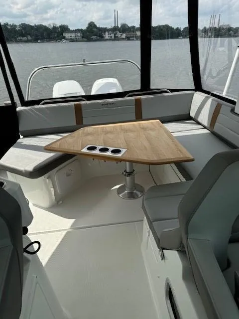Slide: The Image of 2024 Beneteau Gran Turismo 32 interior with seating and wooden table, overlooking a serene water view. - 11