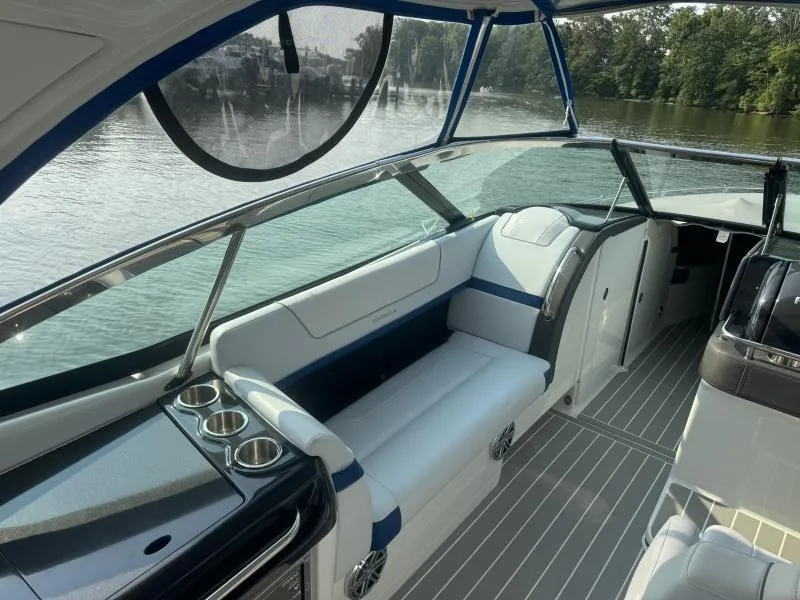 Slide: The Image of 2020 Formula Boats 350 Crossover Bowrider interior with seating and cup holders on a calm lake. - 21