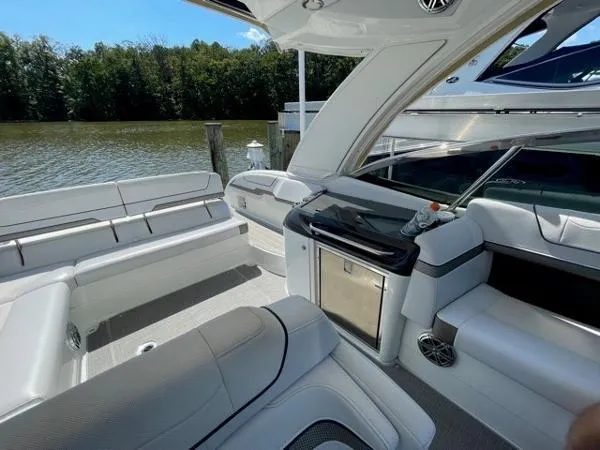 Slide: The Image of 2019 Formula Boats 350 CBR interior with seating and kitchenette, docked by a serene lake. - 14