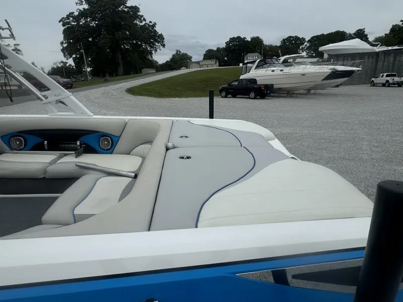Slide: The Image of 2013 Malibu Wakesetter 23 LSV boat interior with seating and speakers, parked outdoors. - 9
