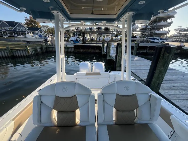 Slide: The Image of 2020 Edgewater 280 Center Console boat docked at marina, featuring dual seats and outboard motors. - 6