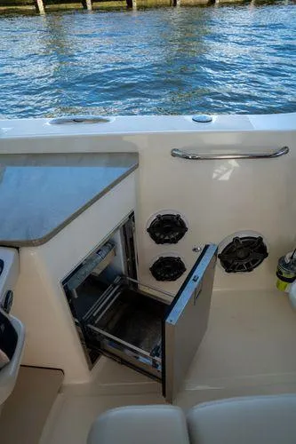Slide: The Image of 2020 Boston Whaler 350 Realm boat interior with open storage compartment by the water. - 10