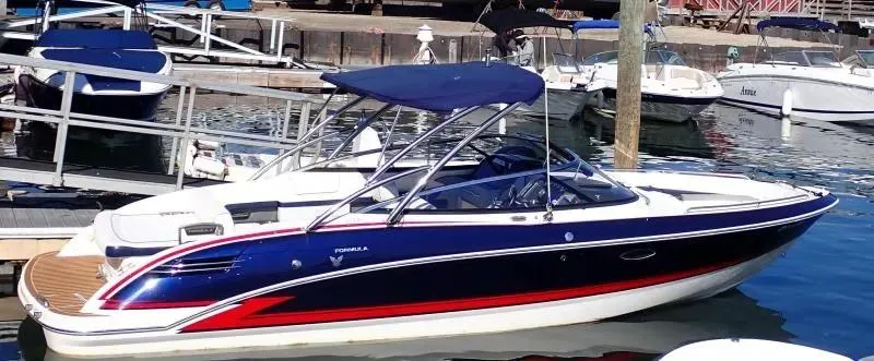 Slide: The Image of 2014 Formula 270 Bowrider boat docked in a marina, featuring a sleek design and blue canopy. - 1