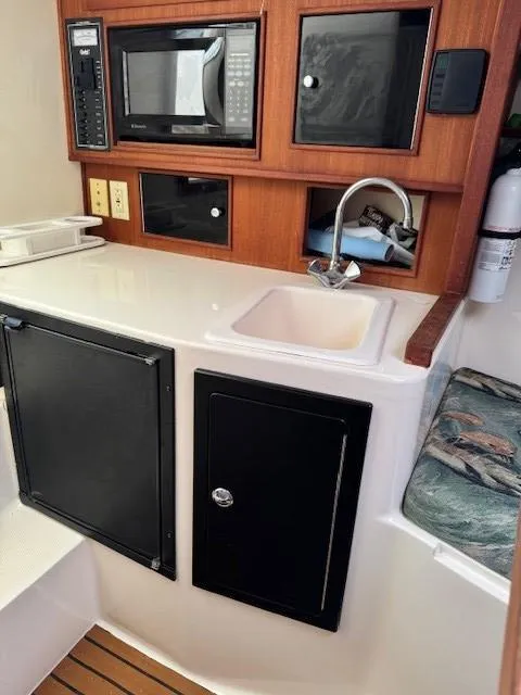 Slide: The Image of 2006 Carolina Classic 280 Express boat interior with kitchenette, sink, and microwave. - 23