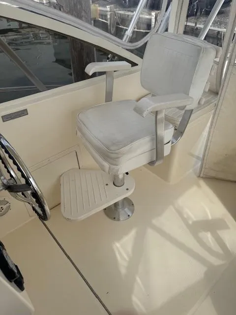 Slide: The Image of Captain's chair on 2006 Carolina Classic 280 Express boat, featuring white upholstery and metal armrests. - 25