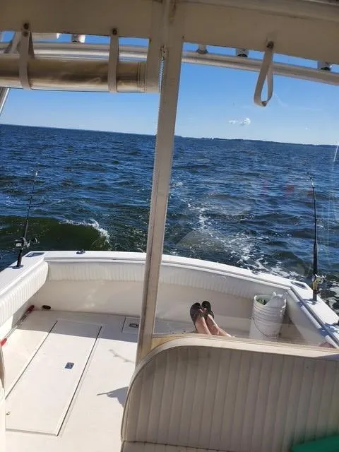 Slide: The Image of 2006 Carolina Classic 280 Express boat on open water, with fishing rods and person relaxing. - 8