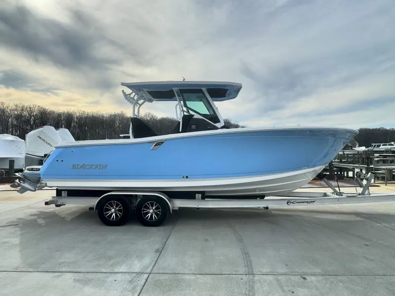 Slide: The Image of 2025 Blackfin 272 Center Console boat on trailer, blue hull, parked outdoors. - 2