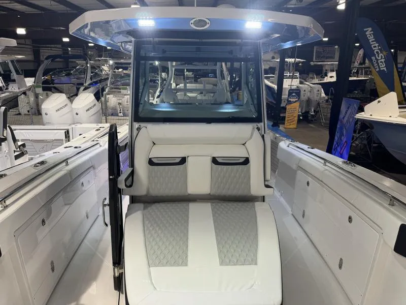 Slide: The Image of 2025 Blackfin 332 boat interior with cushioned seating and modern design in showroom. - 11