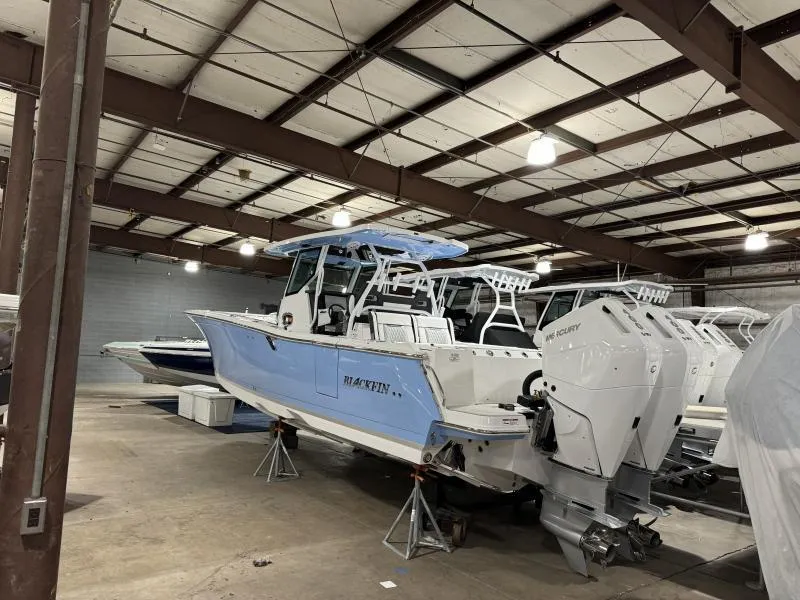 Slide: The Image of 2025 Blackfin 332 boat in warehouse, featuring dual outboard engines and sleek design. - 2