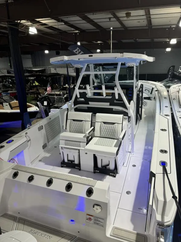 Slide: The Image of 2025 Blackfin 332 boat interior with modern seating and sleek design in a showroom. - 5