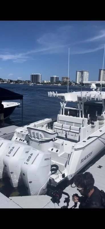 Slide: The Image of 2025 Blackfin 400 boat docked with twin Mercury engines, city skyline in background. - 19