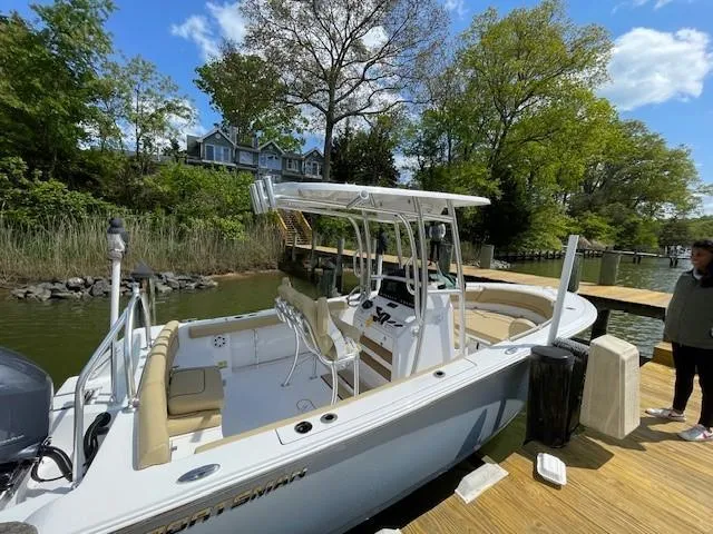 Slide: The Image of 2023 Sportsman 231 Heritage boat docked by a scenic lakeside with trees and a house. - 11