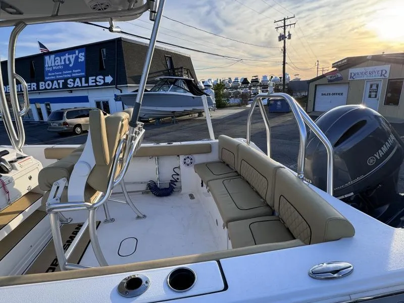 Slide: The Image of 2023 Sportsman 231 Heritage boat at dealership, featuring seating and Yamaha engine. - 16