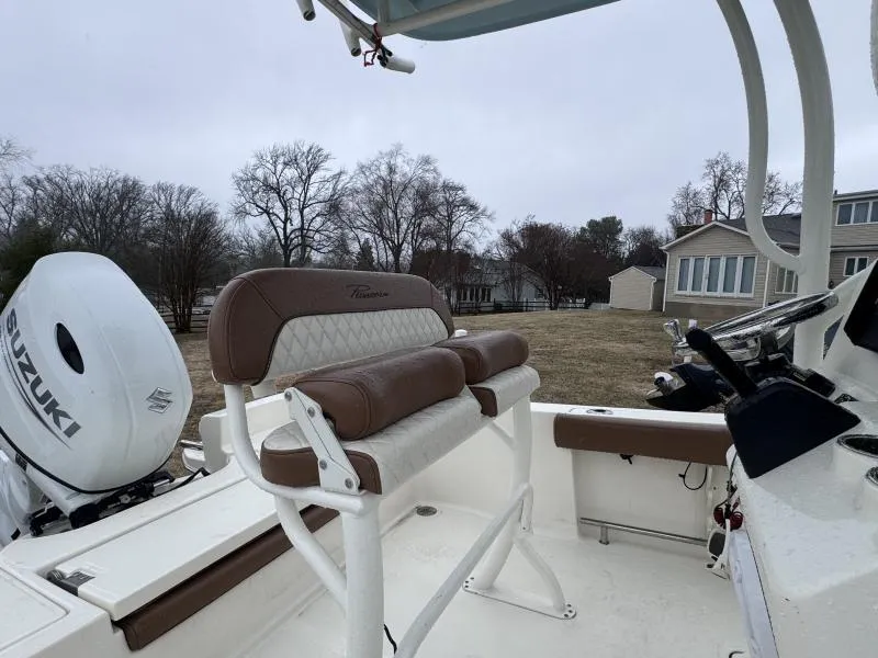 Slide: The Image of 2021 Pioneer 220 Bay Sport boat interior with Suzuki engine, featuring brown seating and steering console. - 11
